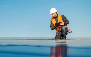 Neues Klimaschutzgesetz: Ein Techniker mit Schutzweste und -helm kontrolliert eine Solaranlage.