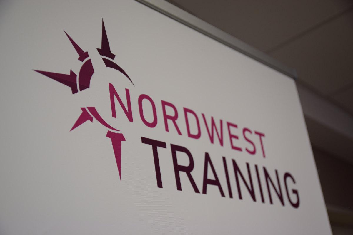 Das Logo von Nordwest Training mit dem Firmennamen auf einer großen weißen Leinwand.