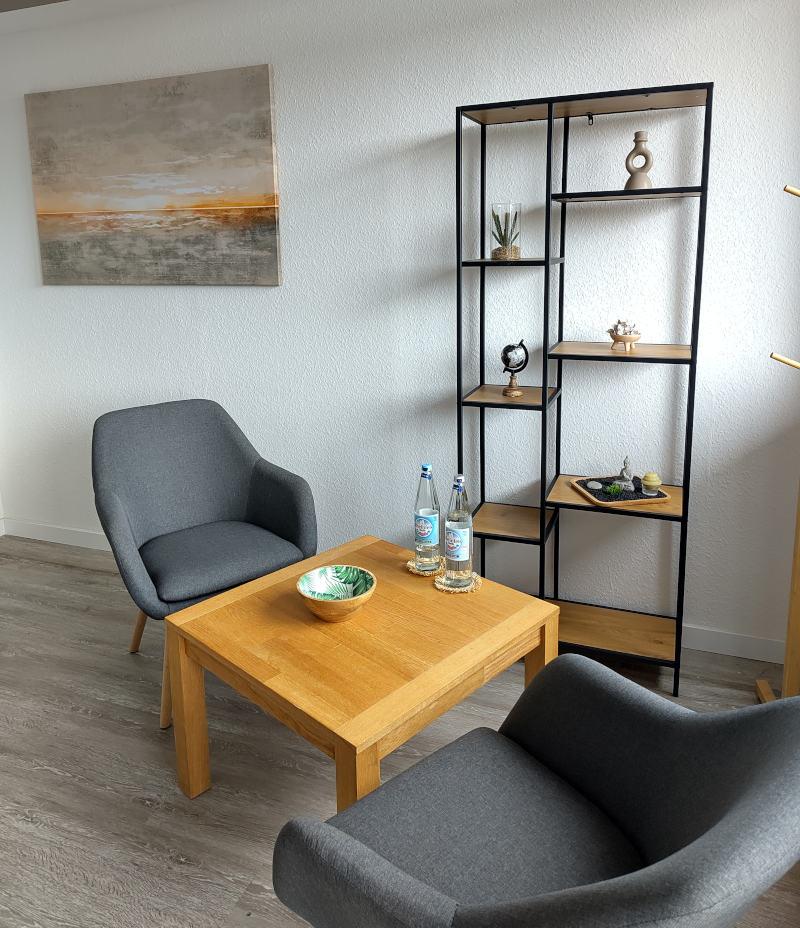 Aufenthaltsraum bei Nordwest Training mit zwei Sesseln, Tisch, offenem Regal und schönem Bild.